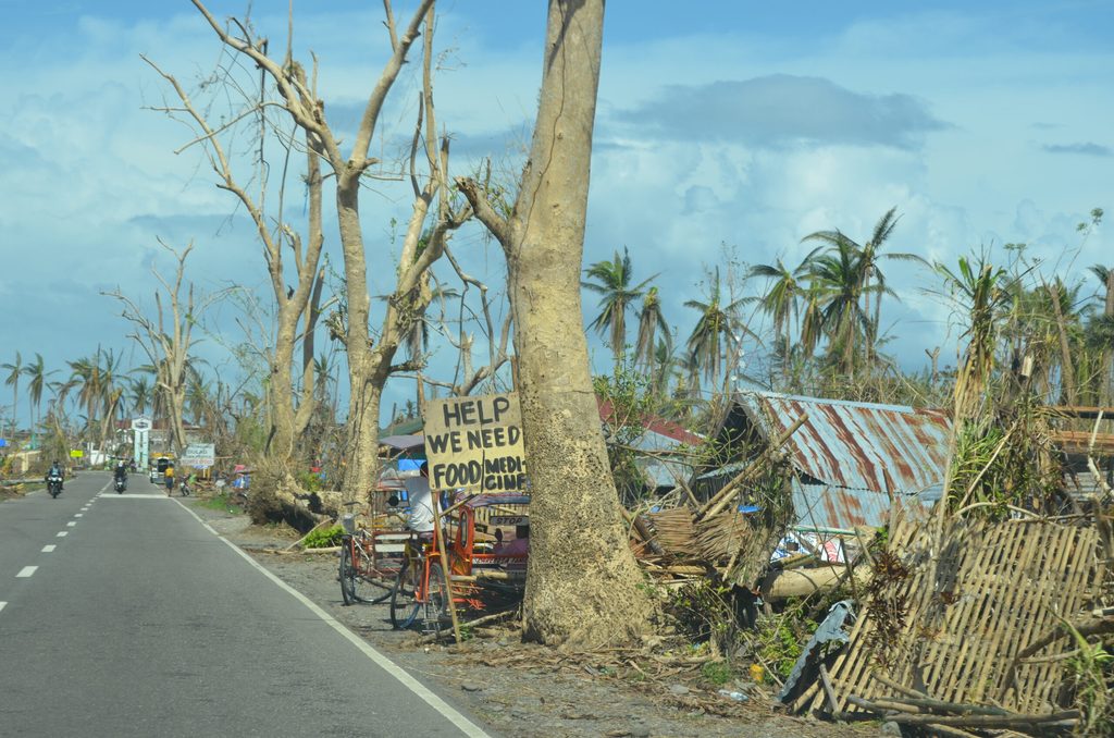 Devastated houses from the Typhoon. A sign that reads "Help we need food/medicine"